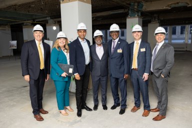 Adelphi team members standing in hard hats at the groundbreaking of a new campus.