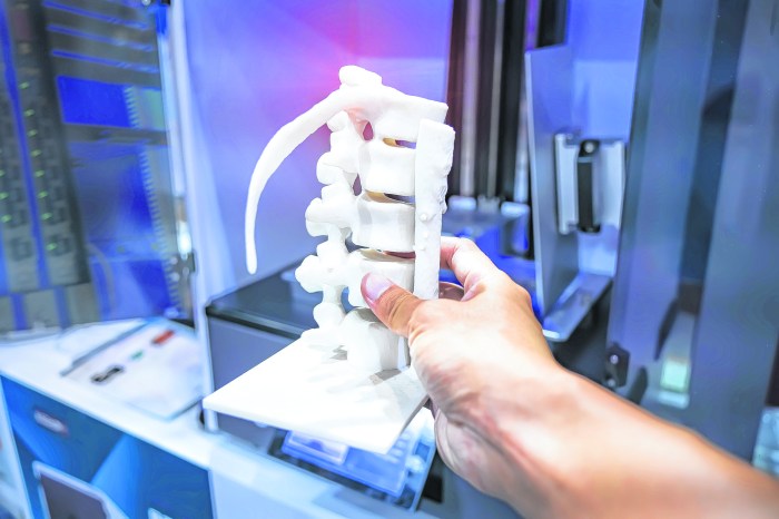 hand with 3d printed human spine in 3d printer.