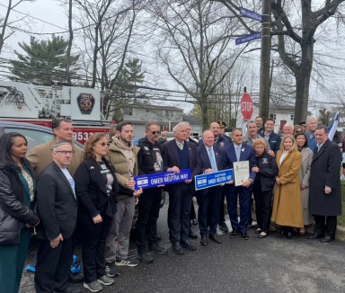 The Neutra family, local leaders and elected officials stand with a sign reading "Captain Omer Neutra Way"