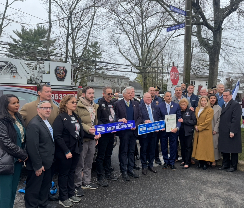The Neutra family, local leaders and elected officials stand with a sign reading "Captain Omer Neutra Way"