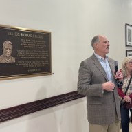 Richard McCord and his wife, Mary (L. to R.) next to the plaque recognizing his 34 years of dedication to Glen Cove, now displayed in City Hall.