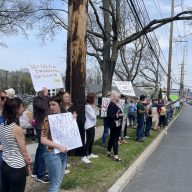 People gathered outside a Tesla dealership in Manhasset to protest against the actions of the president's administration on the 250th anniversary of the start of the Revolutionary War