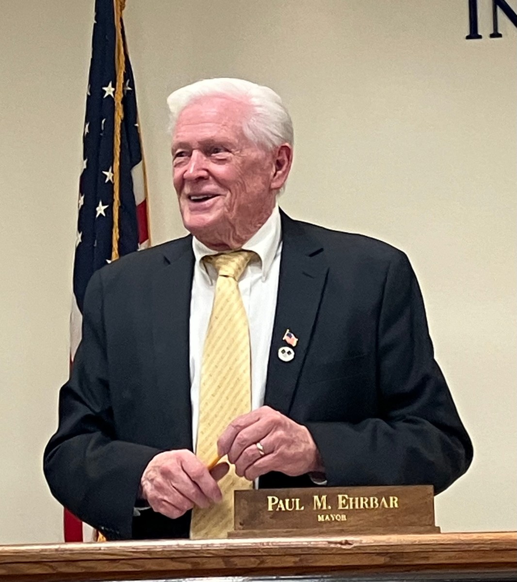 Williston Park Mayor stands and smiles at board table.