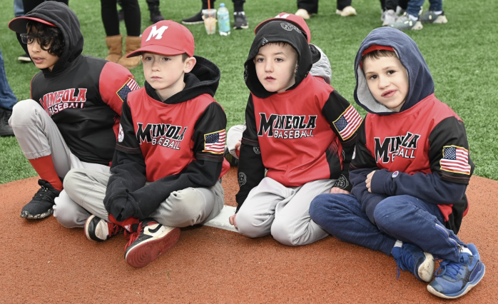 Four kids sit on a track at Mineola's Little League parade on Saturday.