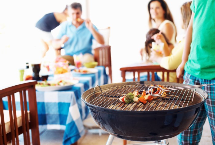 Focus on barbecue with family in background