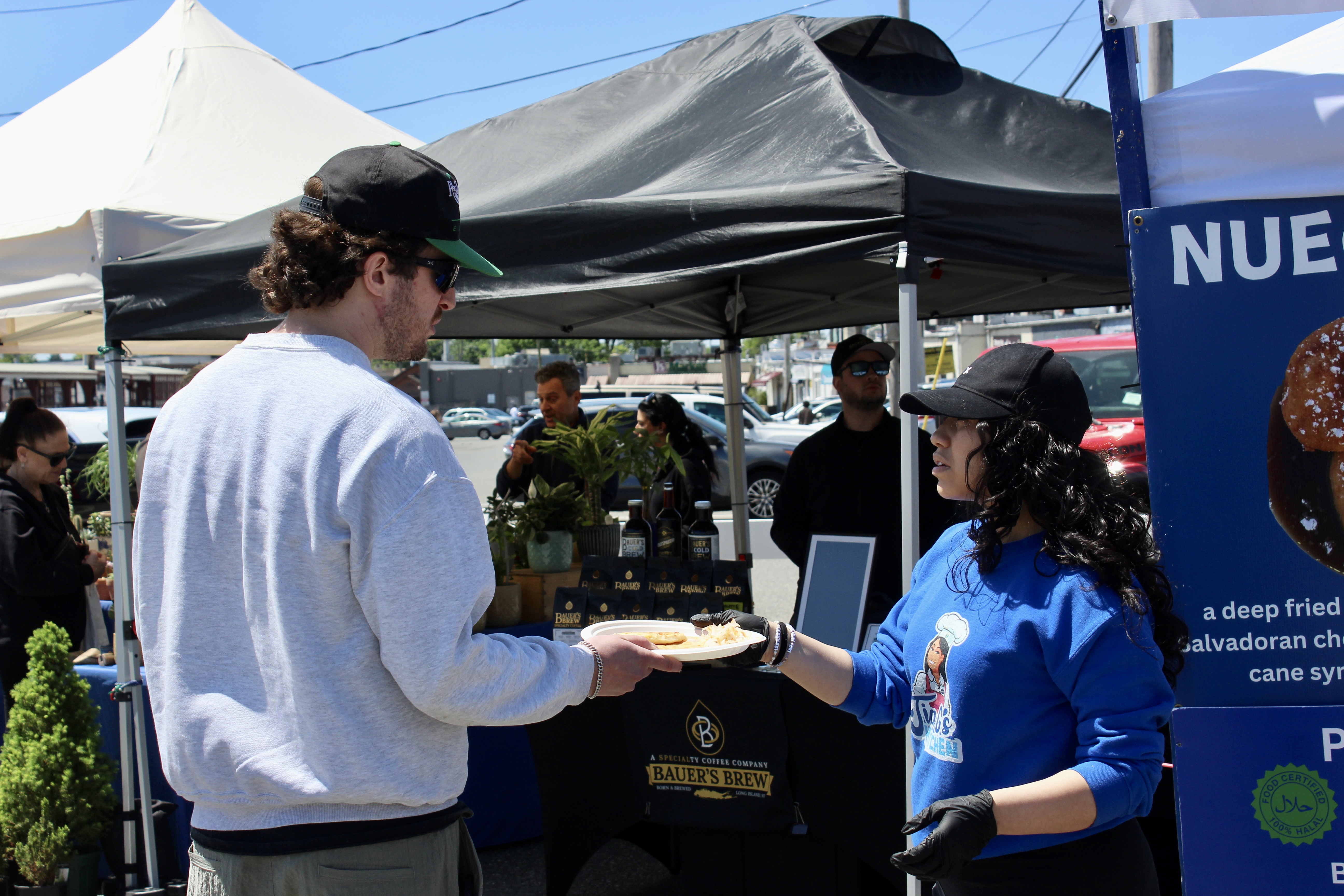 An employee of Tia G's Kitchen hands a customer his pupusas.