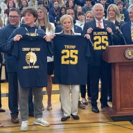 A Massapequa High School senior, the head of the U.S. Department of. Education, Linda McMahon and Nassau County Executive Bruce Blakeman (L. to R.) with Massapequa Chiefs shirts