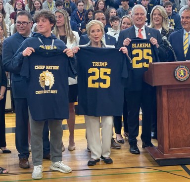 A Massapequa High School senior, the head of the U.S. Department of. Education, Linda McMahon and Nassau County Executive Bruce Blakeman (L. to R.) with Massapequa Chiefs shirts