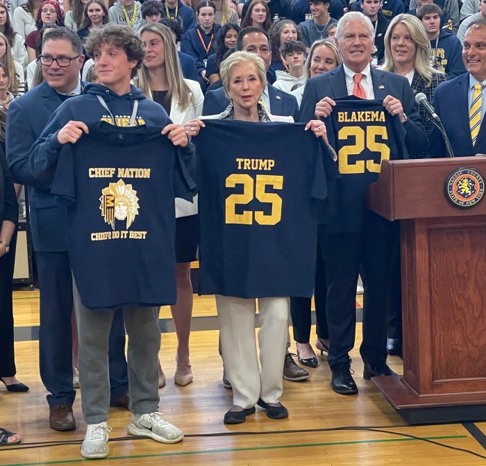 A Massapequa High School senior, the head of the U.S. Department of. Education, Linda McMahon and Nassau County Executive Bruce Blakeman (L. to R.) with Massapequa Chiefs shirts