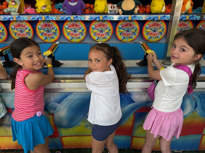 Three girls play a classic carnival game at the Manhasset SCA Fair.