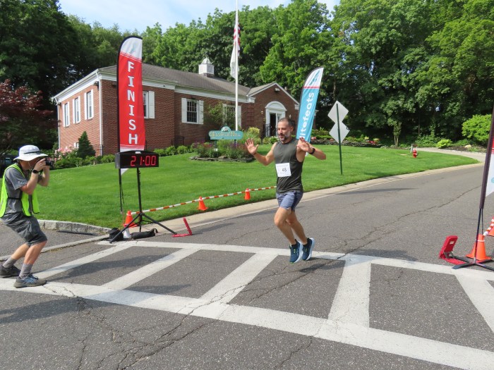 A runner crosses the finish line for the Katie Oppo Memorial 5K in Manhasset.