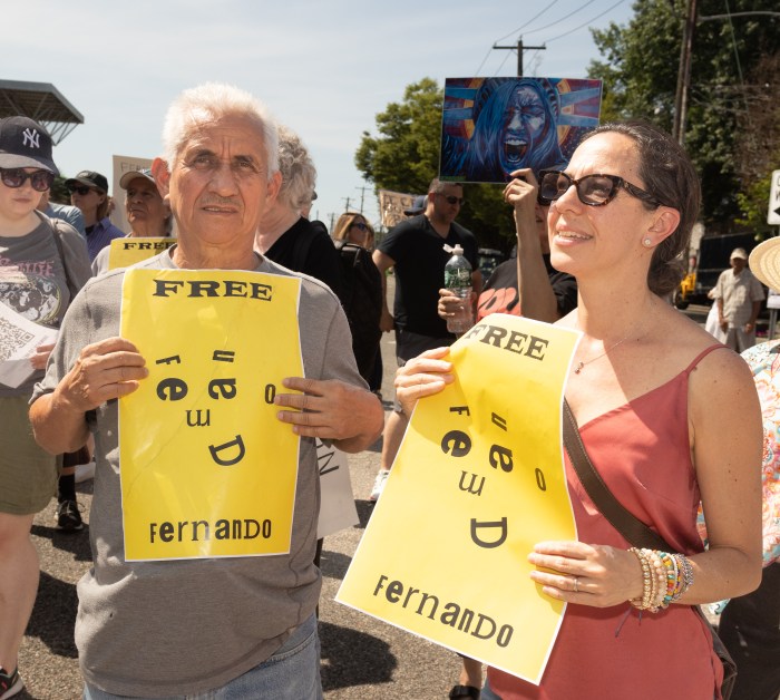 Jorge Albert, Mejia's father (L.) and Ana Agon (R.) hold up signs reading "Free Fernando"