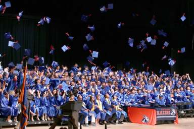 Great Neck North seniors throw their caps into the air at their graduation commencement.