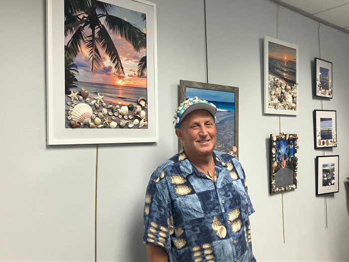 Michael Weinstein stands in front of his beach photography at the Jericho Library