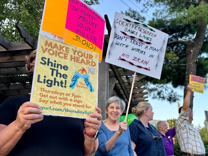 Demonstrators wave signs at the "Make Your Voice Heard" vigil across from the Great Neck Diner.
