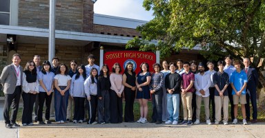 Syosset High School principal John Durante (Far L.) and Syosset Superintendent Thomas Rogers (Far R.) stand with the 24 seniors who were named National Merit semifinalists.