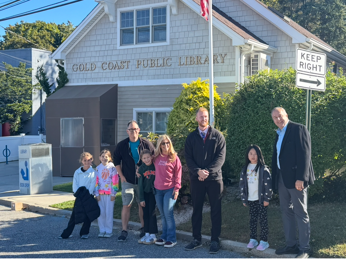 Library representative Michael Morea (third from L.) and principal Tom Sheehan (Center R.) stand with students and staff in front of the current Gold Coast Library building.