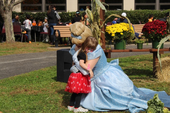 Cinderella hugs a young child at the Village of East Hills Spooktacular.
