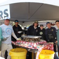 Volunteers display freshly shucked oysters during the 42nd annual Oyster Fest at Theodore Roosevelt Memorial Park in Oyster Bay, celebrating local seafood and community traditions.