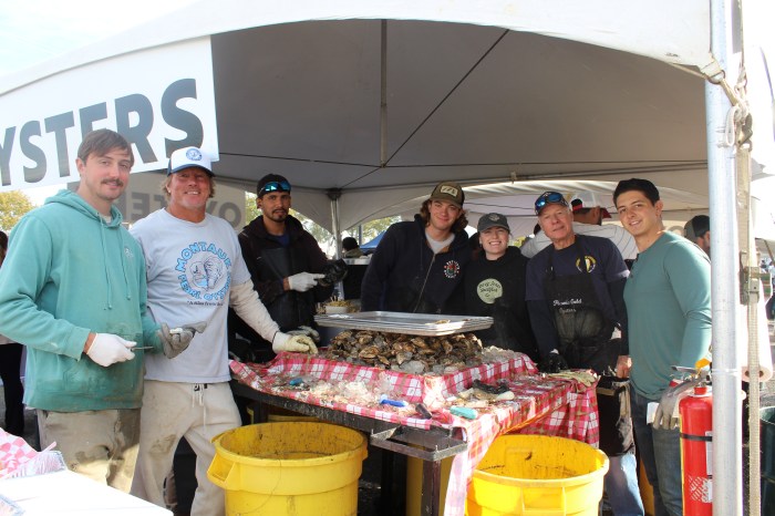 Volunteers display freshly shucked oysters during the 42nd annual Oyster Fest at Theodore Roosevelt Memorial Park in Oyster Bay, celebrating local seafood and community traditions.
