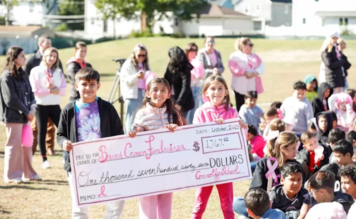 Students hold the check symbolizing the money they raised for breast cancer research.