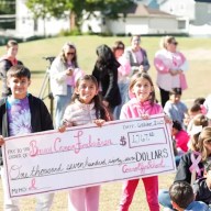 Students hold the check symbolizing the money they raised for breast cancer research.