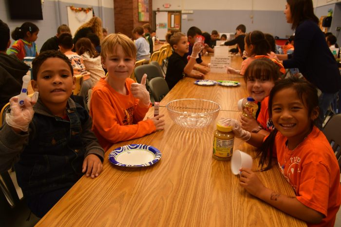 Students holding ingredients for zucchini bread.