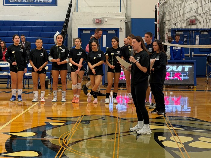 Roslyn Varsity Girls Volleyball team holding flowers in memory of Tara Berkowitz.
