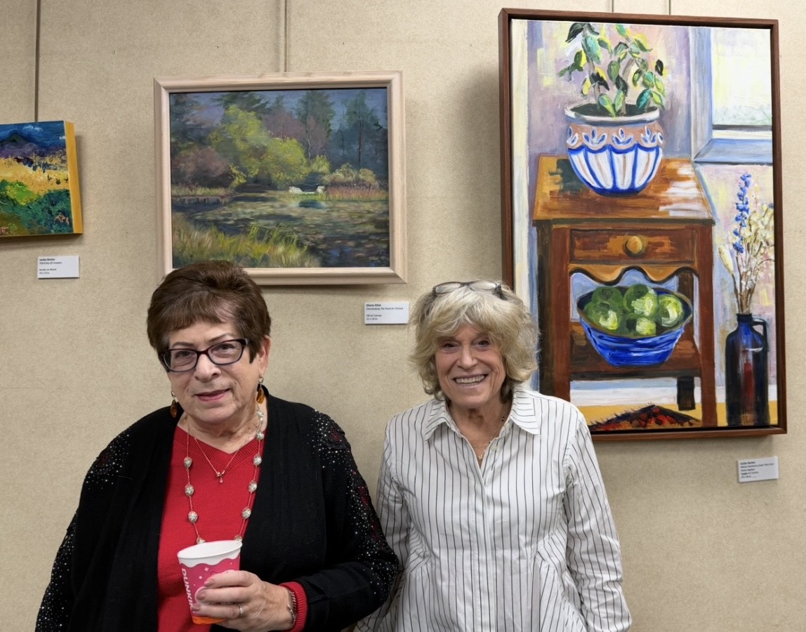 Artists Gloria Glick and Jackie Becker posed in front of their paintings, are on display at Great Neck Plaza's Village Hall.