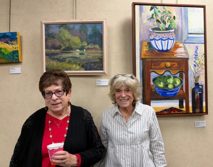 Artists Gloria Glick and Jackie Becker posed in front of their paintings, are on display at Great Neck Plaza's Village Hall.