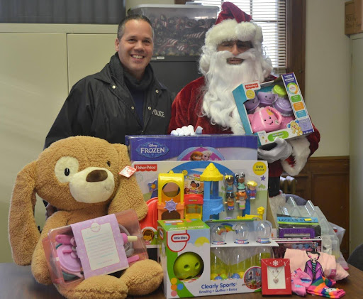 Port Washington Police Detective Anthony Guzzello with Santa and some of the toys donated by generous local residents and businesses.
