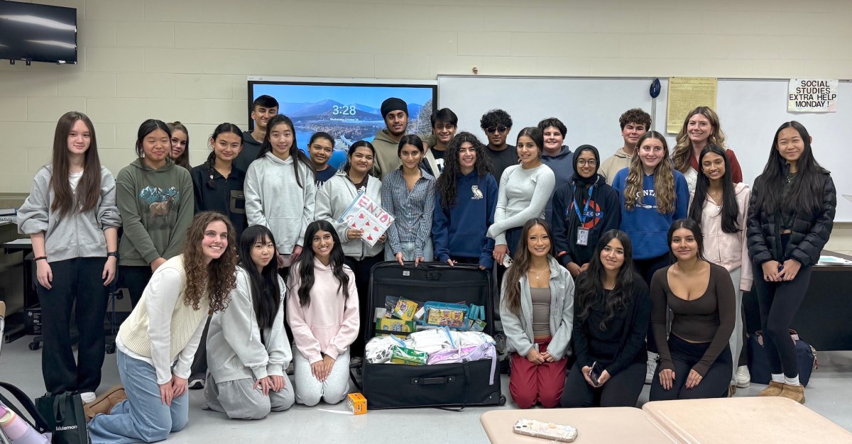 Herricks High School HICAP Club members with a suitcase full of eyeglasses and school supplies for Rwandan children.
