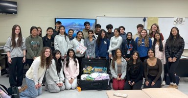 Herricks High School HICAP Club members with a suitcase full of eyeglasses and school supplies for Rwandan children.