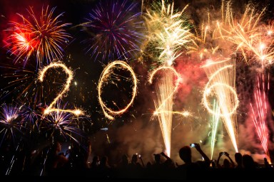 2026 written with fireworks as a background and crowd of celebrating people