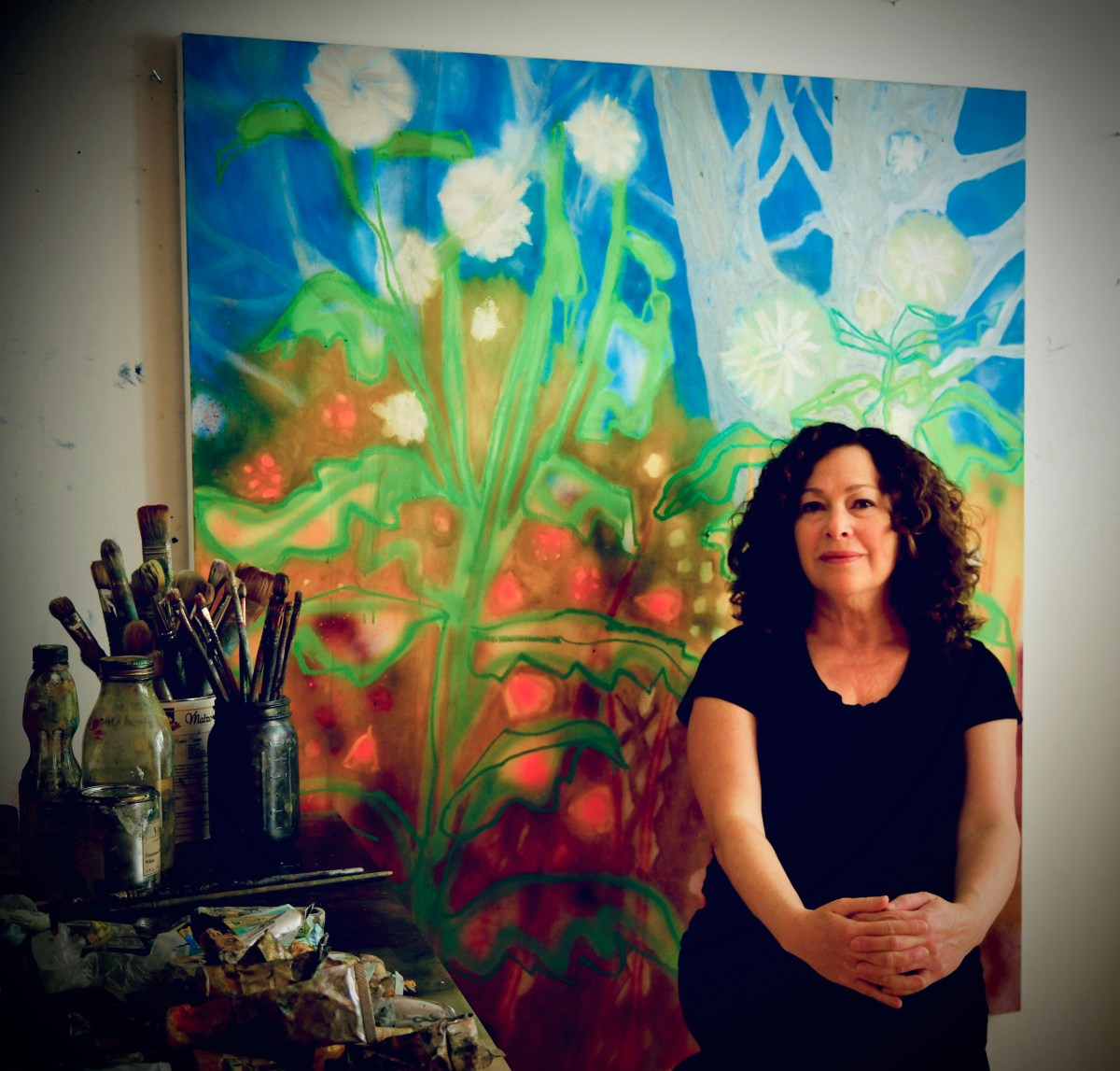 Port Washington based artist Rachelle Kreiger with her painting from her exhibit "Day Dreams and Night Visions" on show at the Port Washington Public Library.