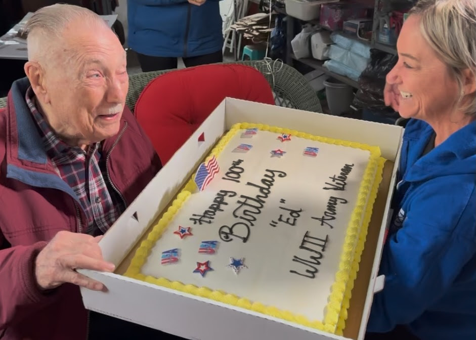 Edward Born, US Army Veteran, is presented with a cake for his 100th birthday.