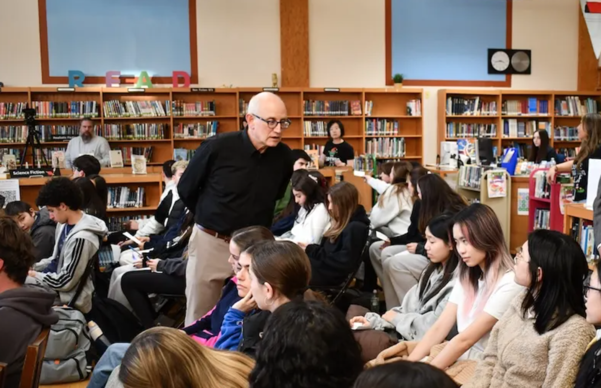 Journalist David L. Marcus (standing) talks to Manhasset students