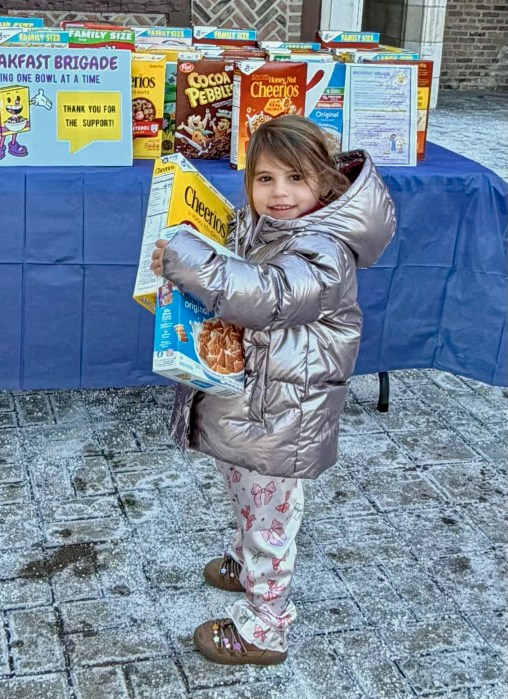 A child donating cereal to the breakfast brigade.