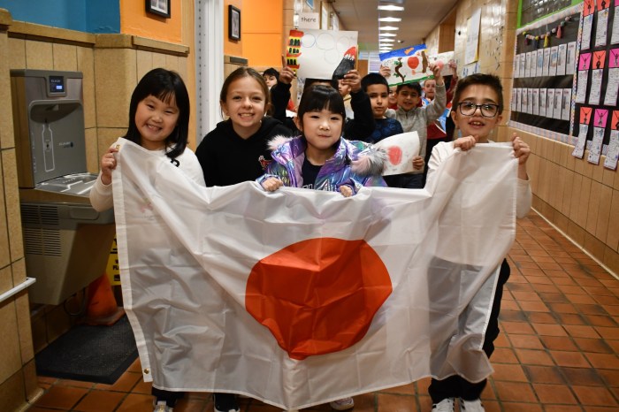 Students carried the flag of Japan in an Olympic parade.