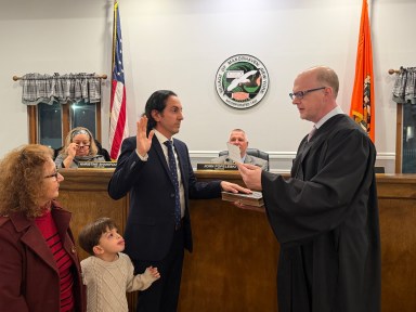 Manorhaven Village Justice William Bodkin (R.) resigned during a board of trustees meeting, then immediately swore in interim justice Gennaro Savastano (L.) with his family by his side.