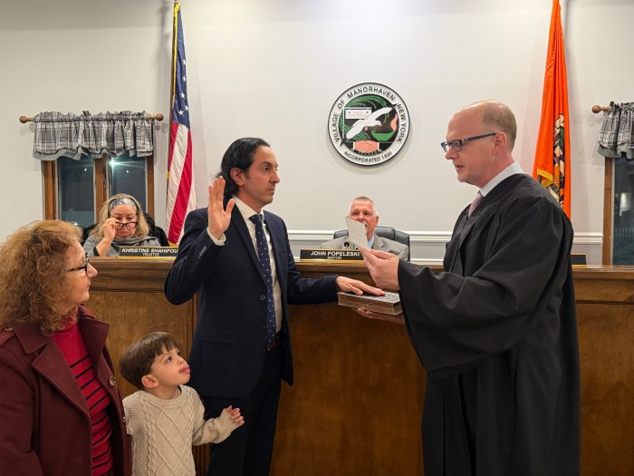Manorhaven Village Justice William Bodkin (R.) resigned during a board of trustees meeting, then immediately swore in interim justice Gennaro Savastano (L.) with his family by his side.